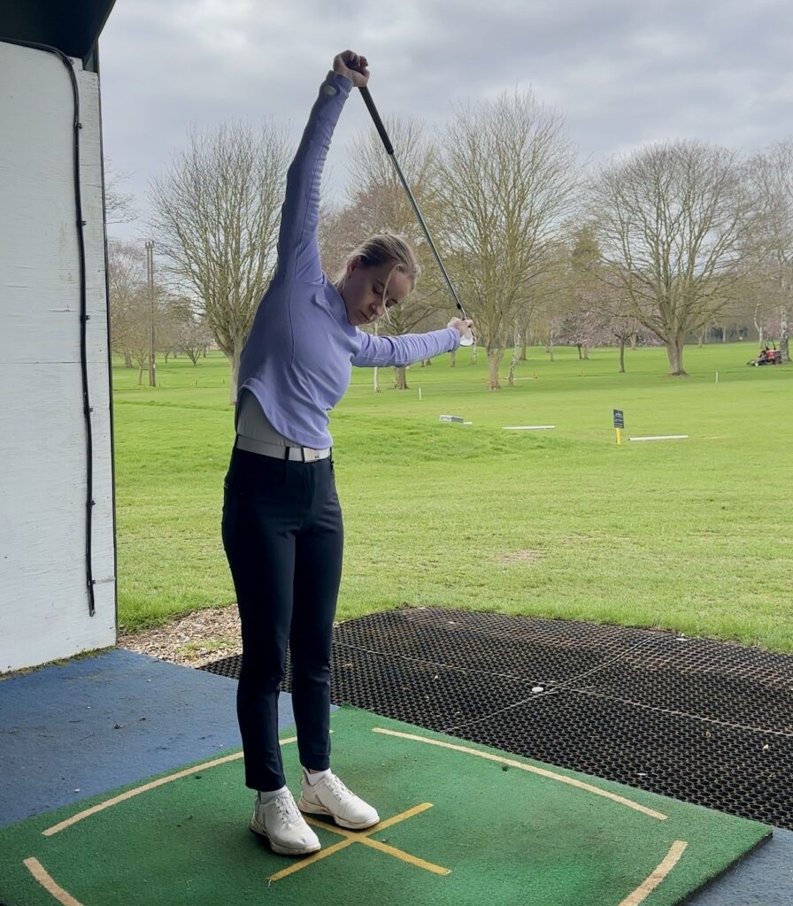 Golfer standing overhead side bend, stretches before golf.